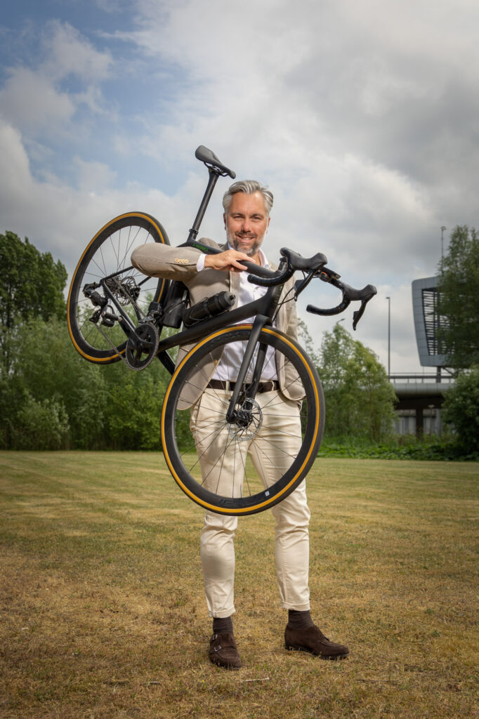 Portretfoto van een bestuurslid van Aafje met een racefiets over zijn arm. Kralingse Zoom, Rotterda, 2022.